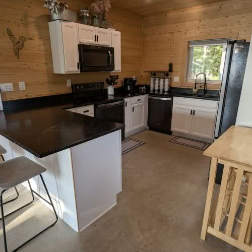 Встроенное освещение и современная мебель на нашей полностью оборудованной кухне создают светлое и уютное пространство для приготовления пищи в доме на берегу озера.